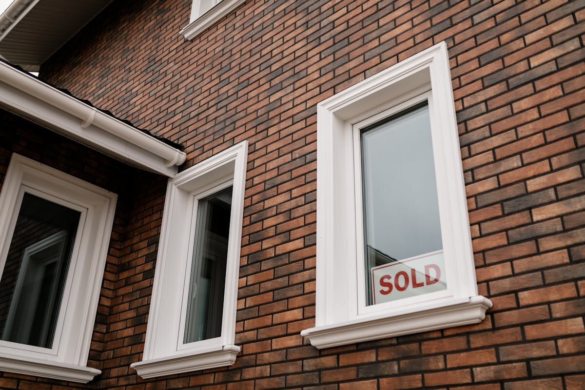 a brick house with a sold sign in the window