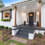 a house with white brick walls and a black door for sale