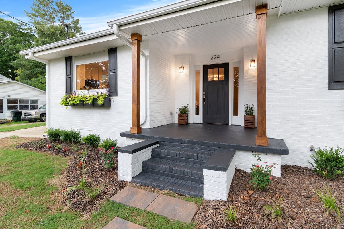 a house with white brick walls and a black door for sale