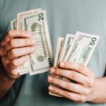 a person counting a bunch of american dollar bills