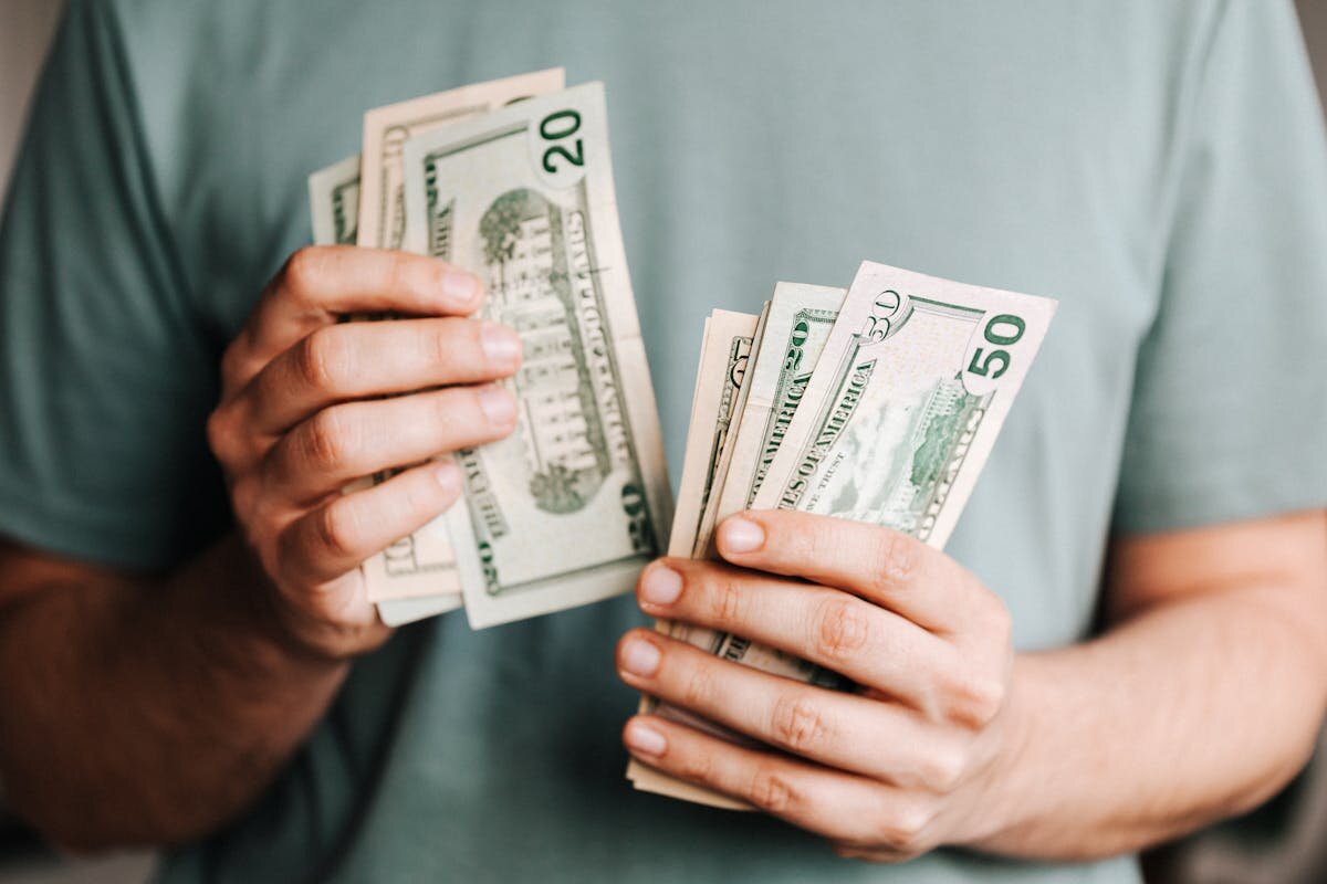 a person counting a bunch of american dollar bills