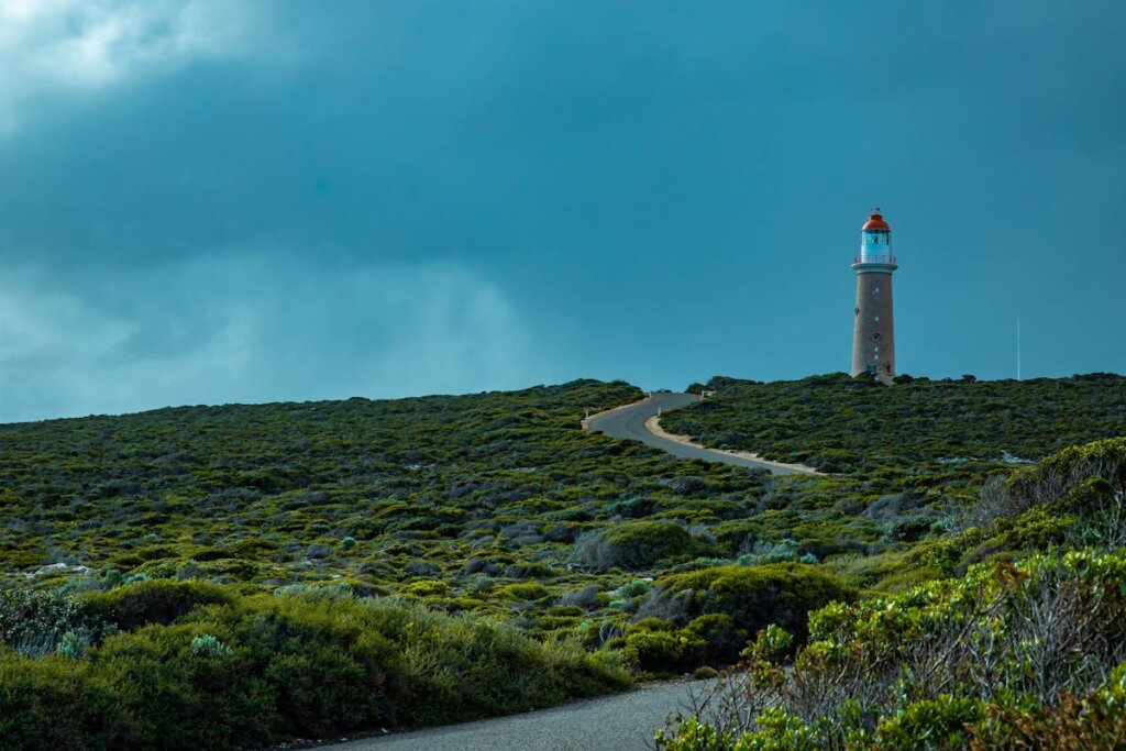A lighthouse on the top of a green hill
