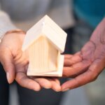 a person holding a small wooden house in their hands