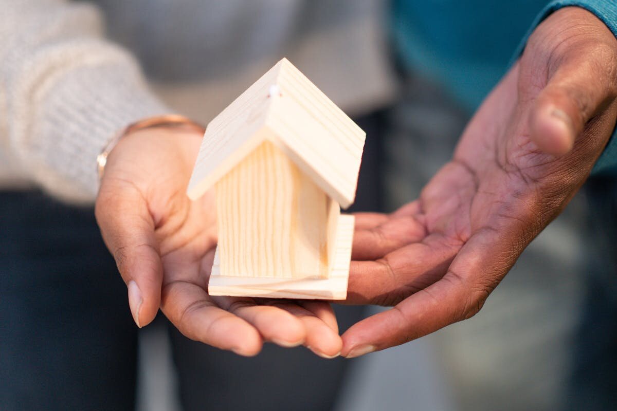 a person holding a small wooden house in their hands