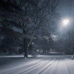 a snowy road with a light shining down on it