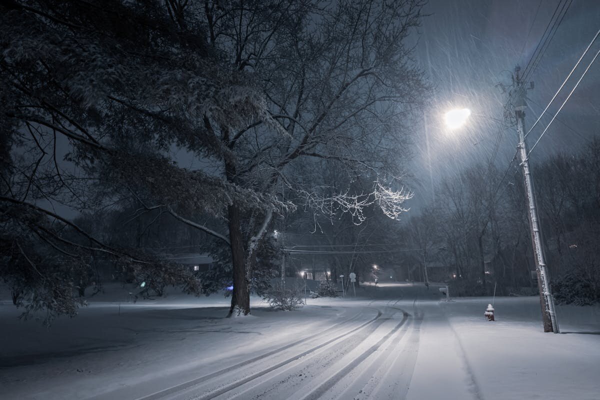 a snowy road with a light shining down on it