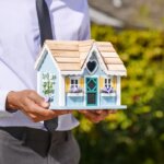 A man holding a small wooden house