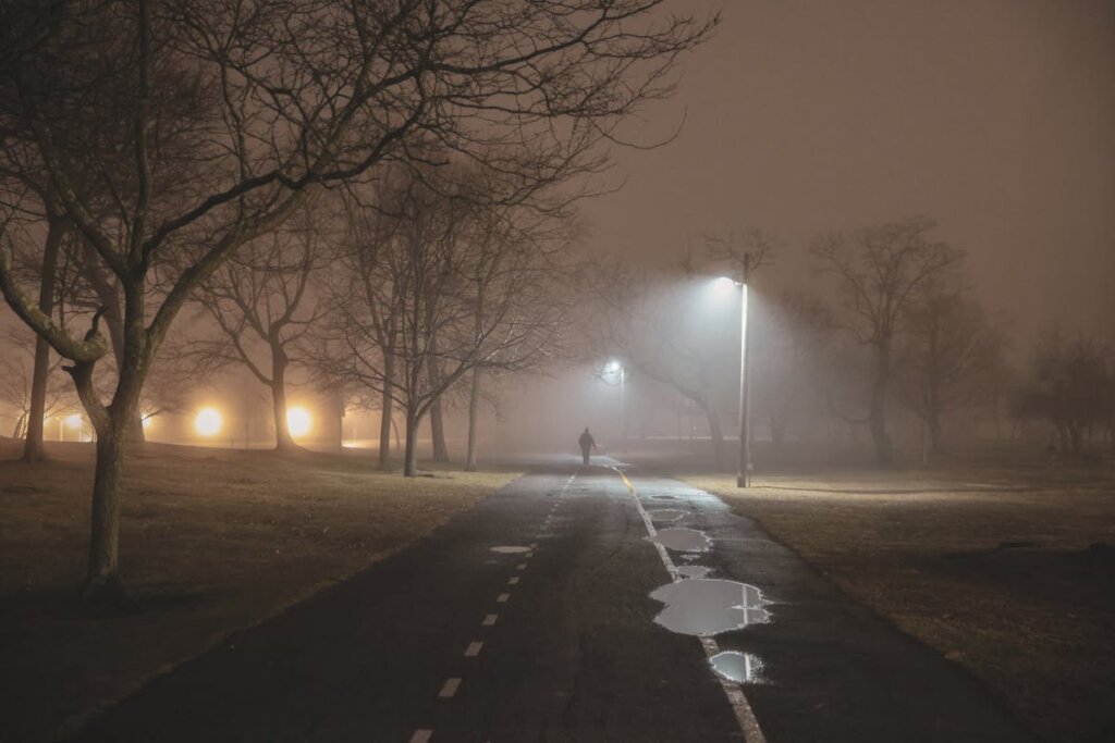 A road with fog all around and a person walking