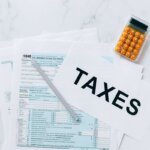 A bunch of tax pages on a table with a calculator next to it