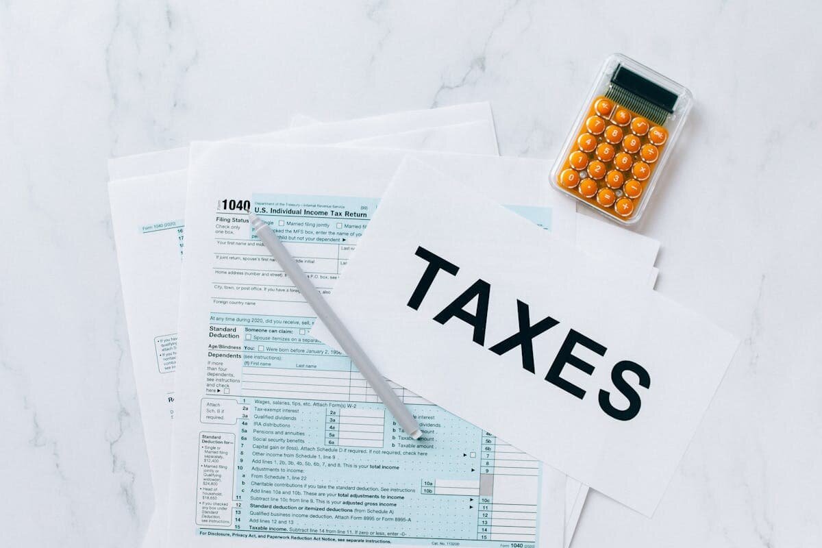 A bunch of tax pages on a table with a calculator next to it