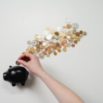 A piggy bank with coins spread out above it