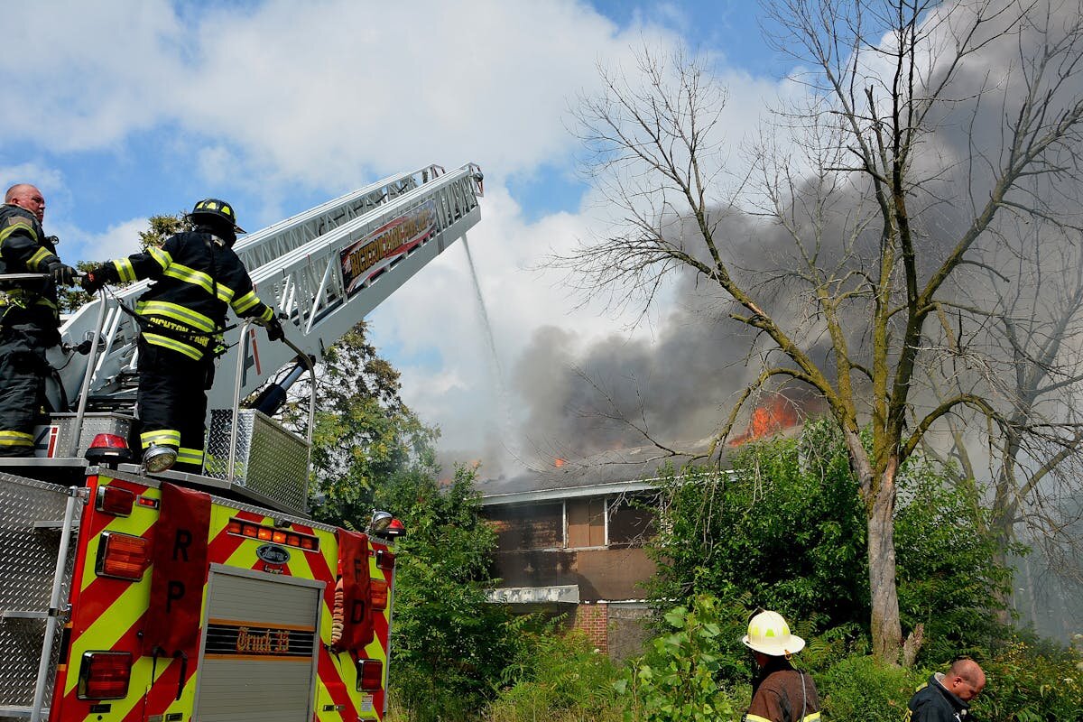A house that is on fire and a firetruck spraying water on it