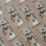 A bunch of 100 dollar bills all laid out evenly on a table