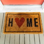 A rug outside of a house door that says home on it