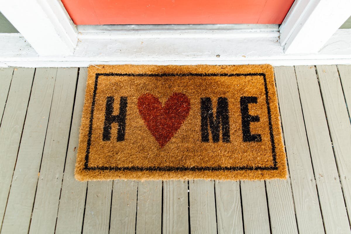 A rug outside of a house door that says home on it