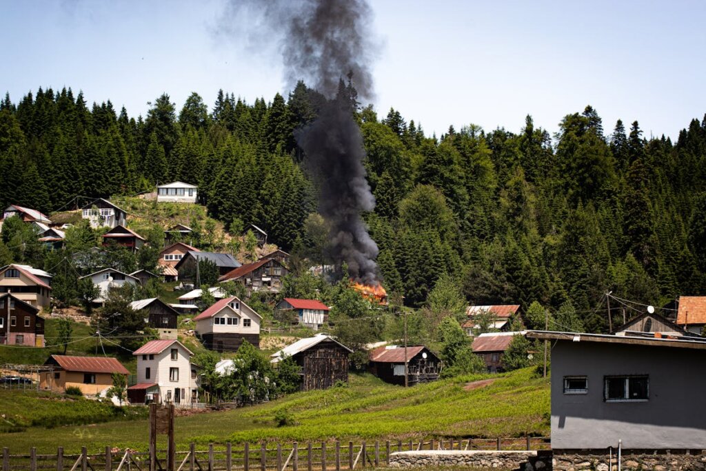 A hill with a bunch of homes and one that is on fire