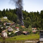 A hill with a bunch of homes and one that is on fire
