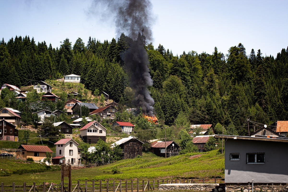 A hill with a bunch of homes and one that is on fire