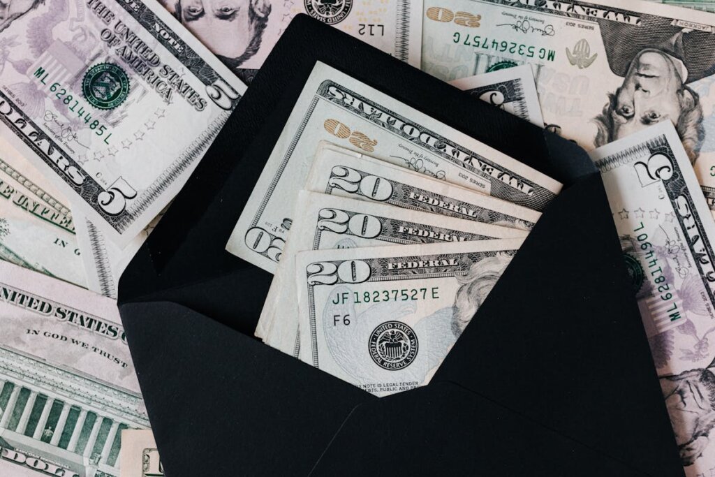 A bunch of US cash sitting in an envelope and on a table