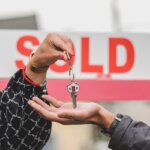 A person handing a key over to another person who purchased the house