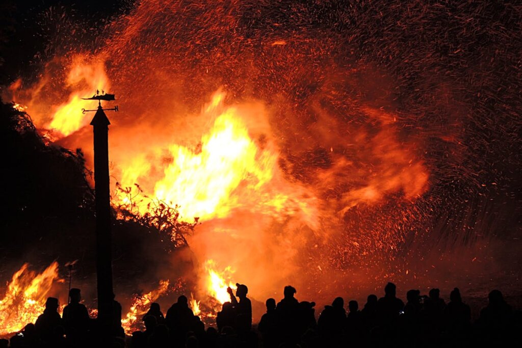 A fire on a house with a bunch of people standing in front of it