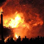 A fire on a house with a bunch of people standing in front of it