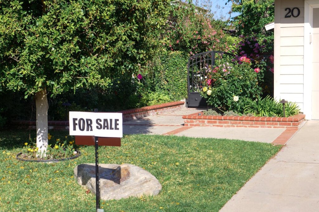 A house with a for sale sign in the front yard