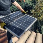A person moving a solar panel to the roof