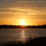 A view of a body of water with a sunset in the backround