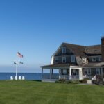 A house with a flag pole in the front yard by the ocean