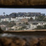 A person looking at a bunch of homes through a metal hole