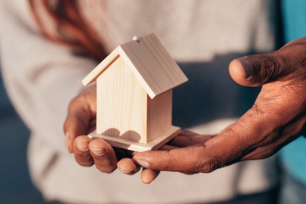 People holding a small wooden replica of a house