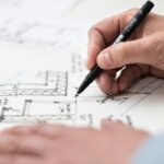 A person drawing blueprints of a house