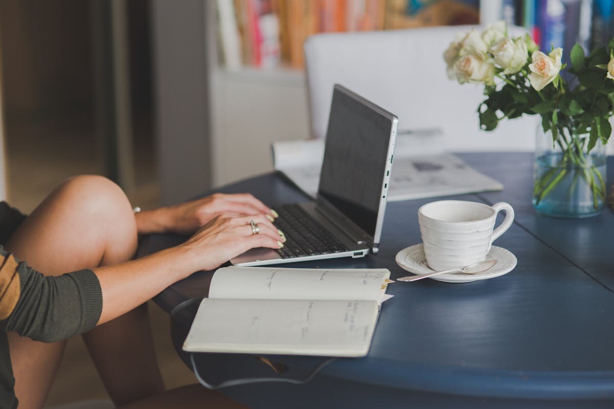 A person sitting on their laptop with a cup of coffee next to them