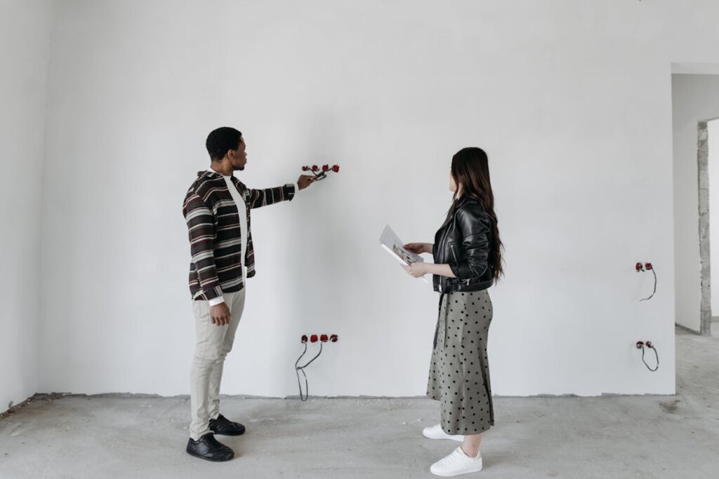 People looking at a wall with electrical wiring sticking out