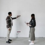 People looking at a wall with electrical wiring sticking out