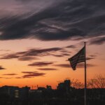 A flag with a city and a sunset in the distance