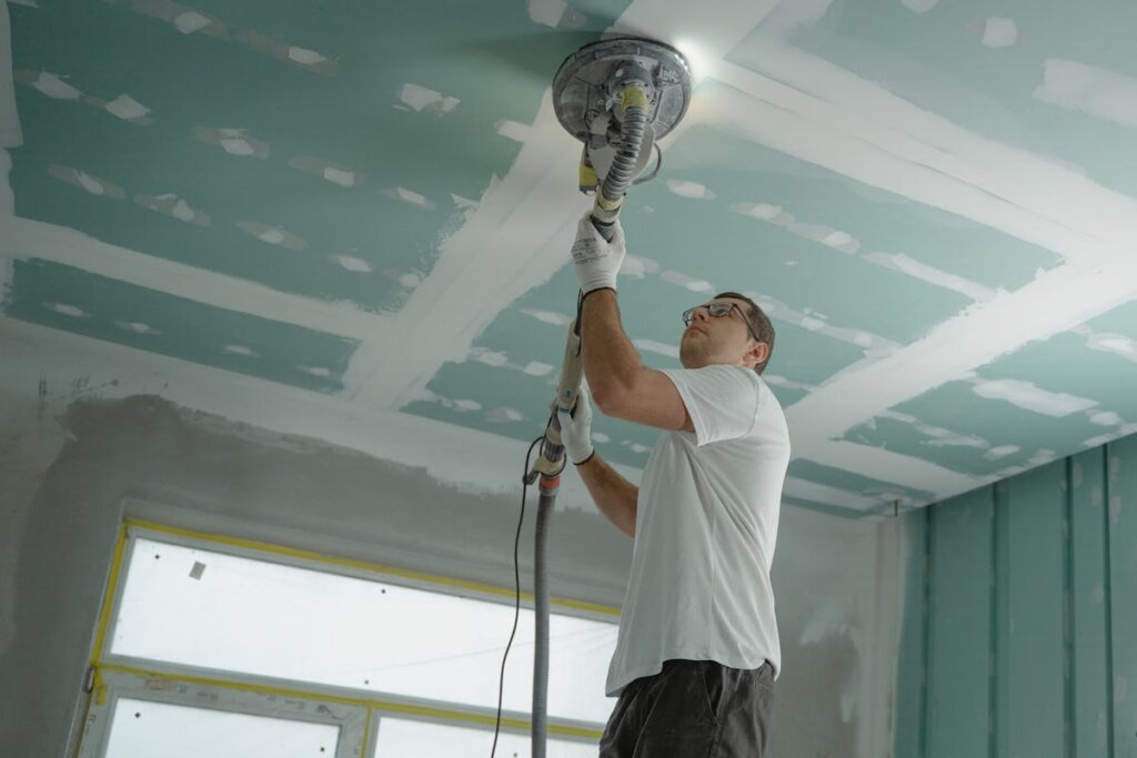 A man doing repairs on a ceiling
