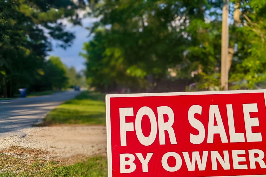 A for sale by owner sign next to a road