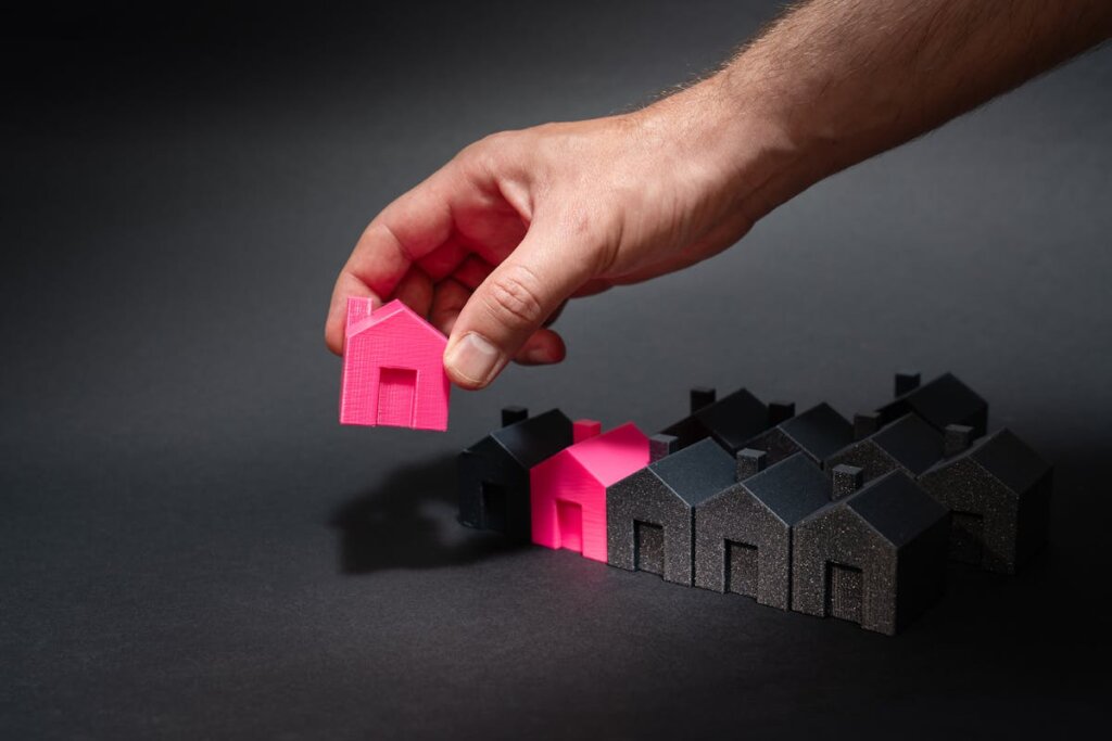 A person placing small houses down onto a black surface