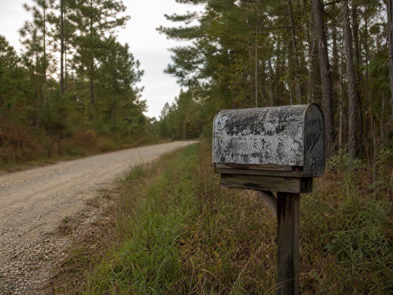Rural mailbox on a dirt road indicating property tax notices.