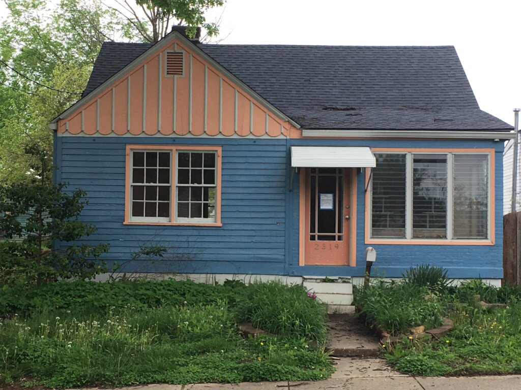 Worn out single story Ginger Bread looking house Blue w/ Peach Accents