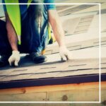 A man fixing a shingle on a roof.