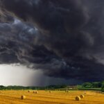 A field with hay bales under storm clouds, captured by an experienced photographer.