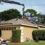 A crane is being used for roof replacement on a house.