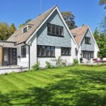 A house with a lawn and trees in the background - important for a new homeowner to know about the roof.