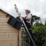 A man inspecting a ladder while looking for things on the roof.