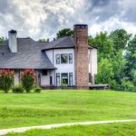 A house with right roof ventilation, located in the middle of a grassy field.