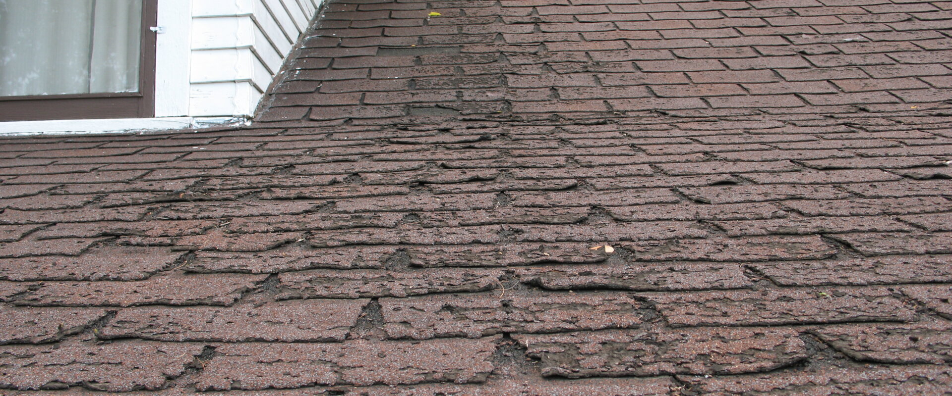 A brown tiled roof displaying signs of problems.