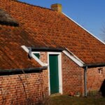 A brick house with a thatched roof facing roof problems.